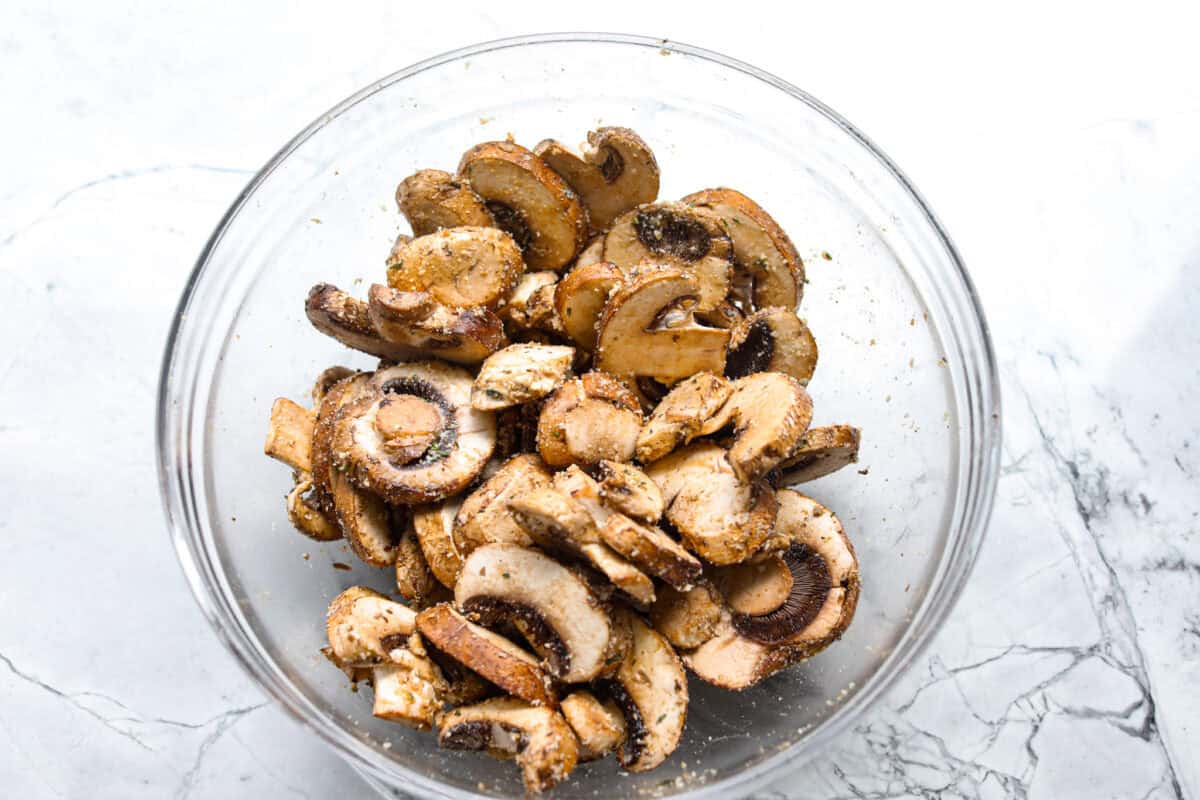 Mushrooms in a bowl mixed with the olive oil, soy sauce, parmesan and seasonings. 