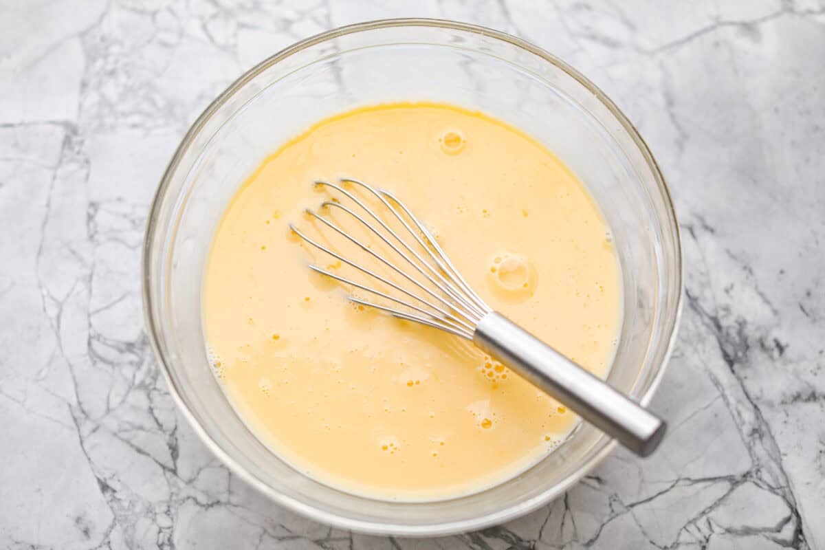 Eggs and milk whisked together in a mixing bowl.