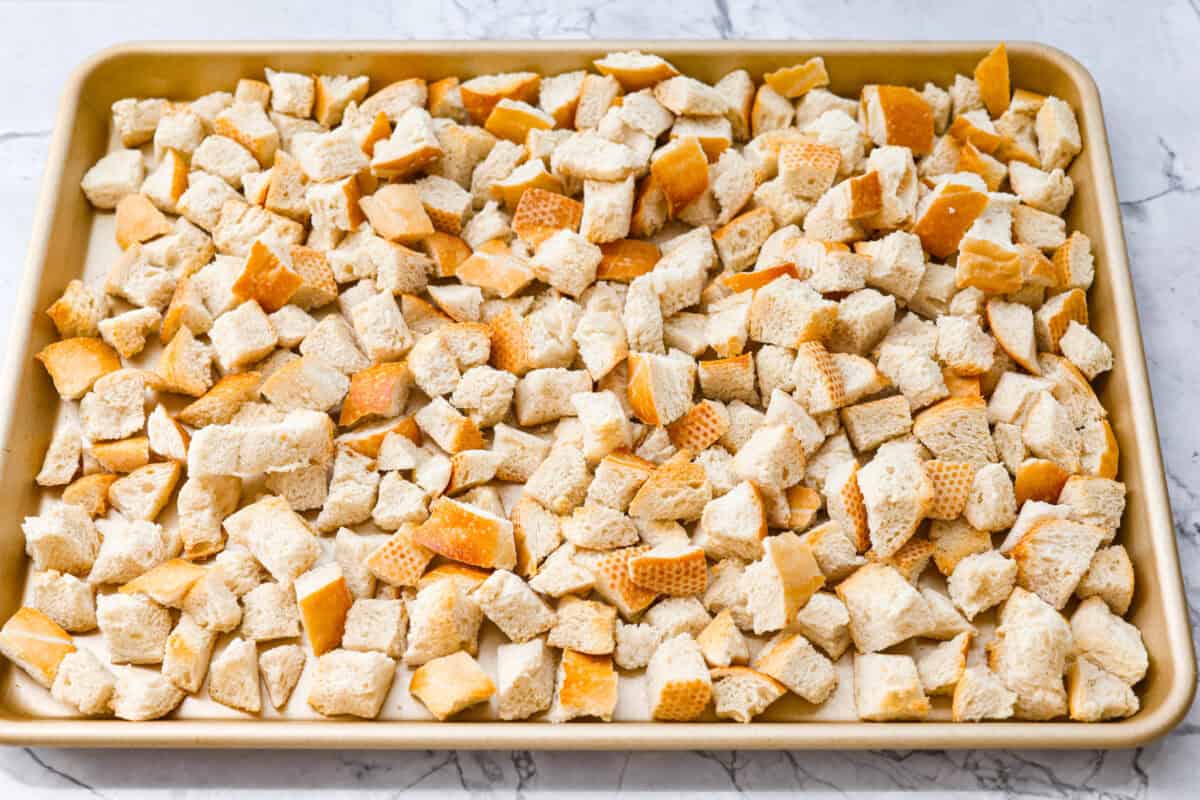 Cubed sourdough bread on a cookie tray.