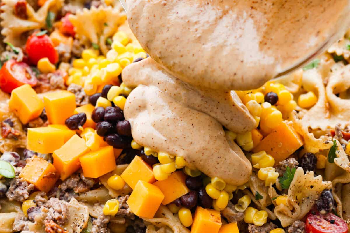 Someone pouring the dressing over the salad ingredients. 