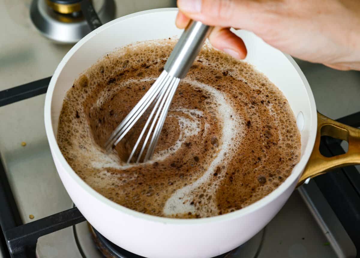 Someone whisking butter, shortening, cocoa, and Dr. Pepper in a saucepan. 