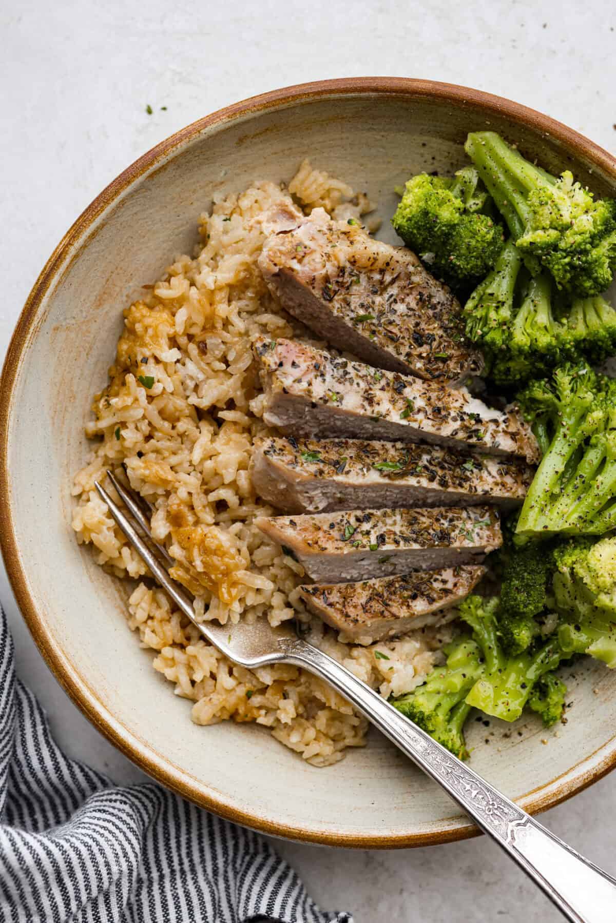 Overhead shot of plated pork chops and rice with broccoli on the side. 