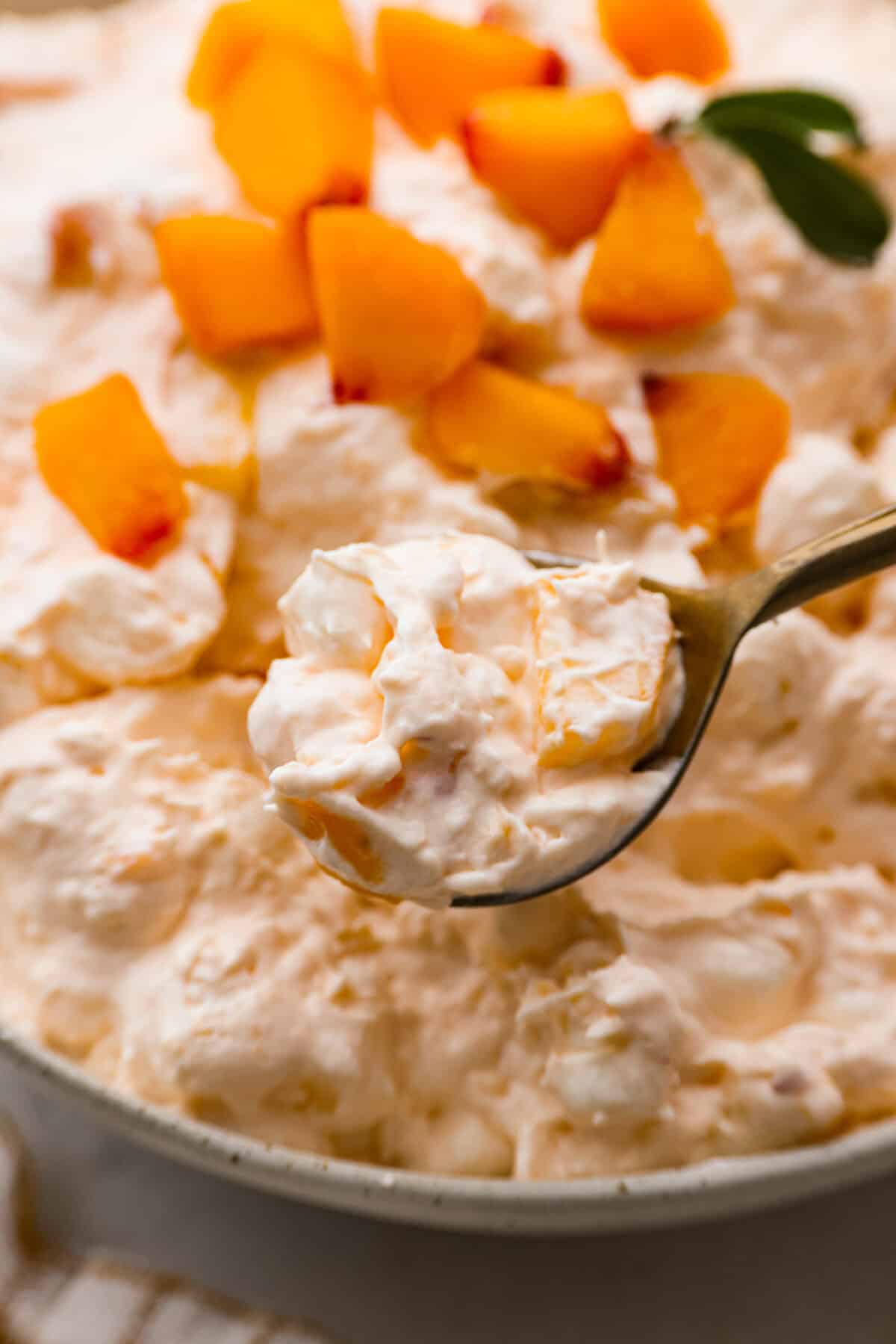 A close up of peach fluff salad on a spoon. 