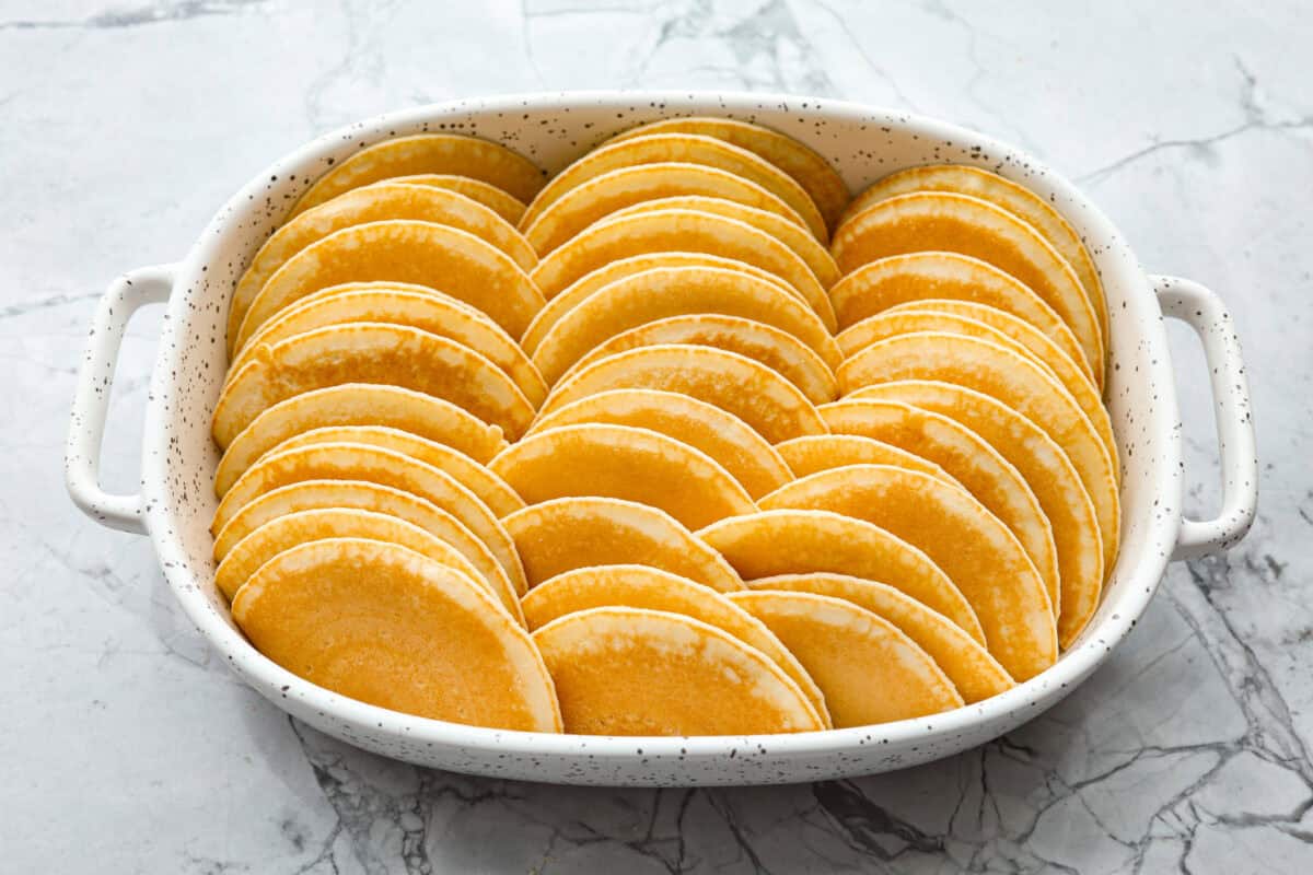 Angle shot of pancakes stacked in baking dish. 