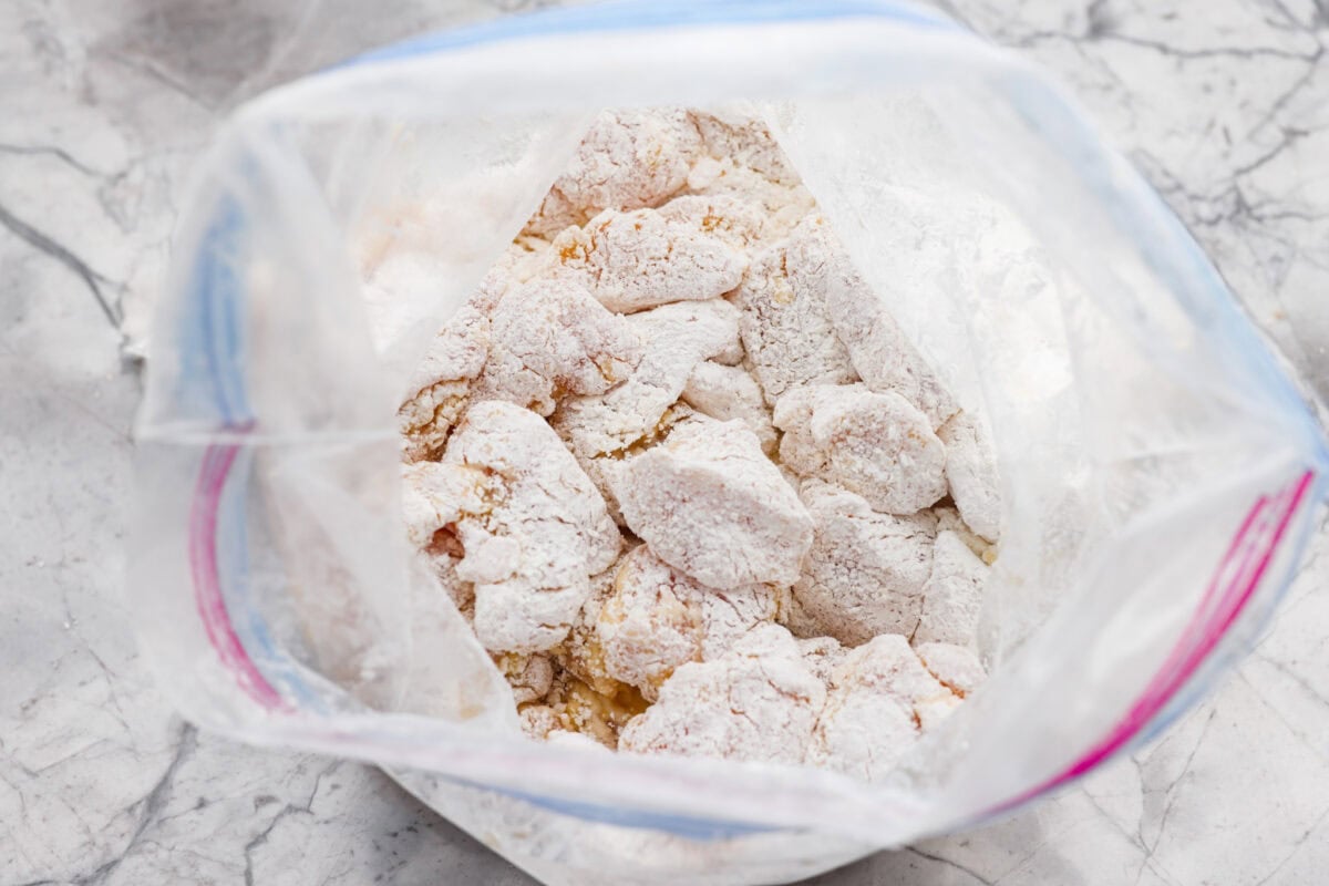 Bite sized pieces of chicken covered in cornstarch in a ziplock bag. 