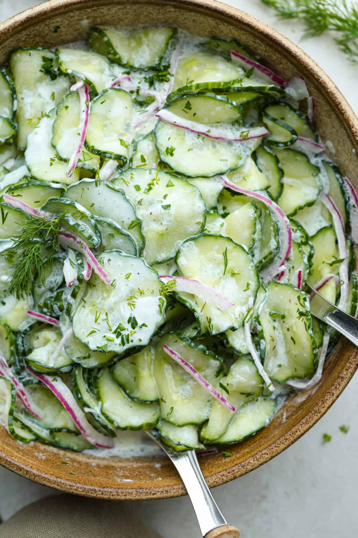 Close up shot of german cucumber salad in a serving bowl. 