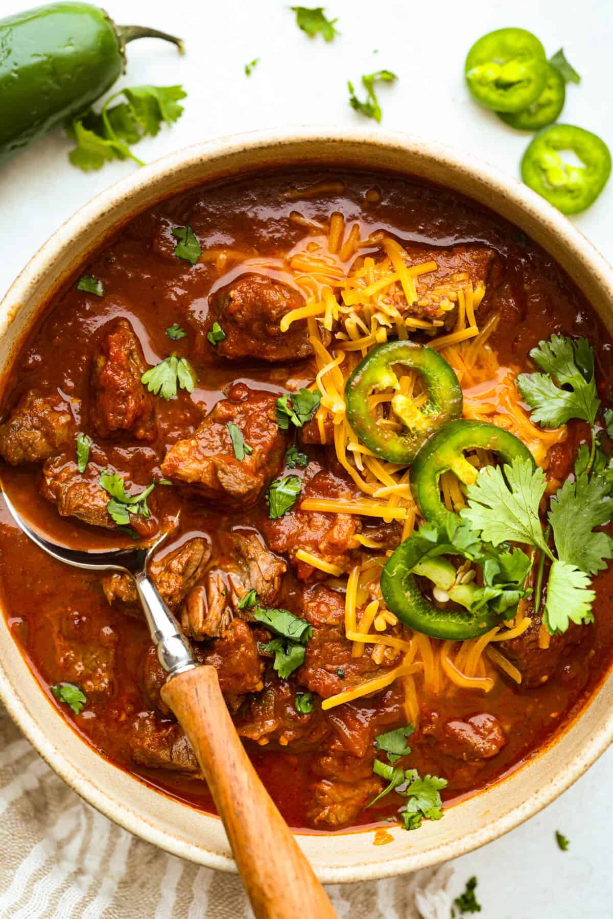 Bowl of Texas chili garnished with shredded cheese, jalapeno slices, and fresh cilantro. 