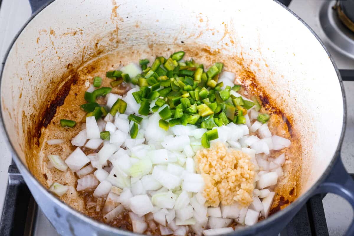 Jalapenos, onion and garlic cooking in the bottom of the dutch oven with the leftovers from the beef. 