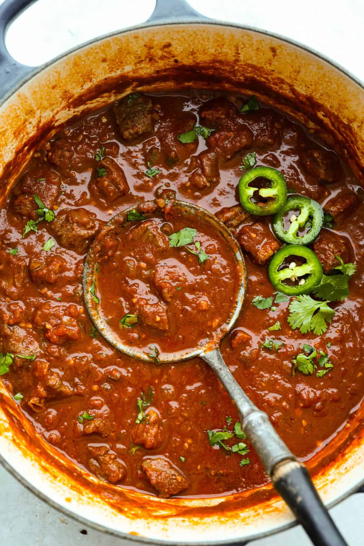 Overhead shot of Texas chili with some fresh cilantro and jalapeños. 