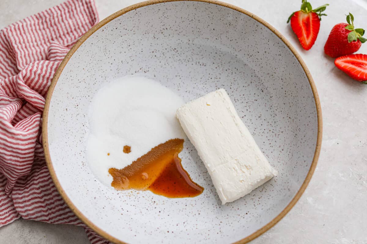 Mixing bowl with sugar, cream cheese, and vanilla extract. 