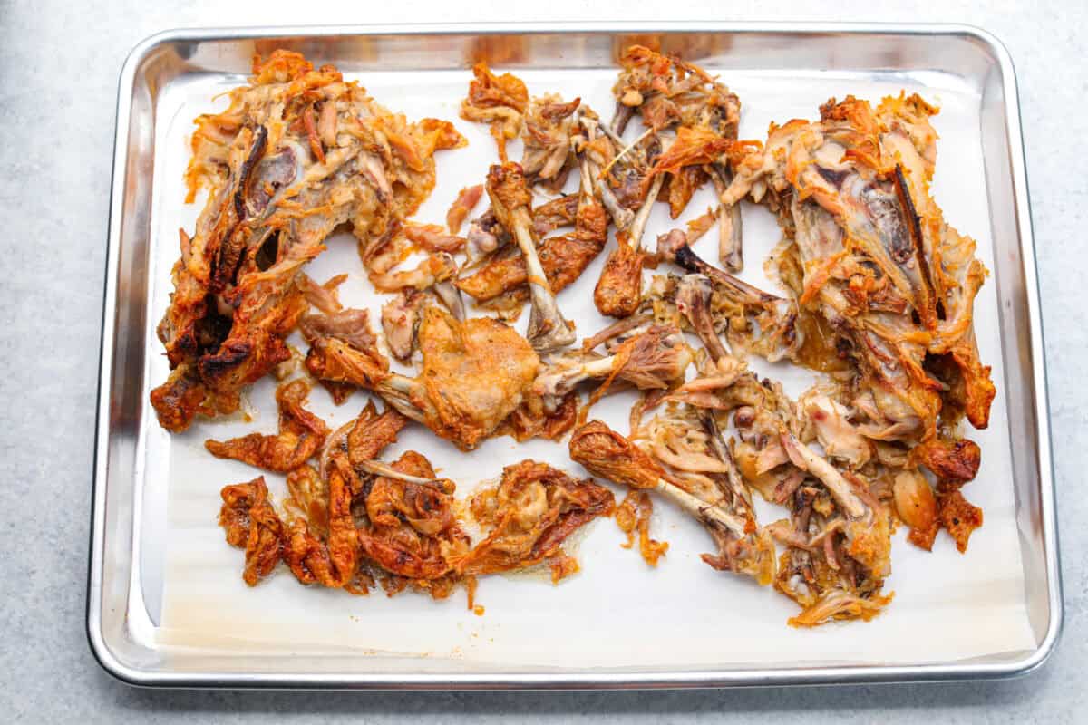 Overhead sho too chicken carcass spread out on a cookie sheet with parchment paper.