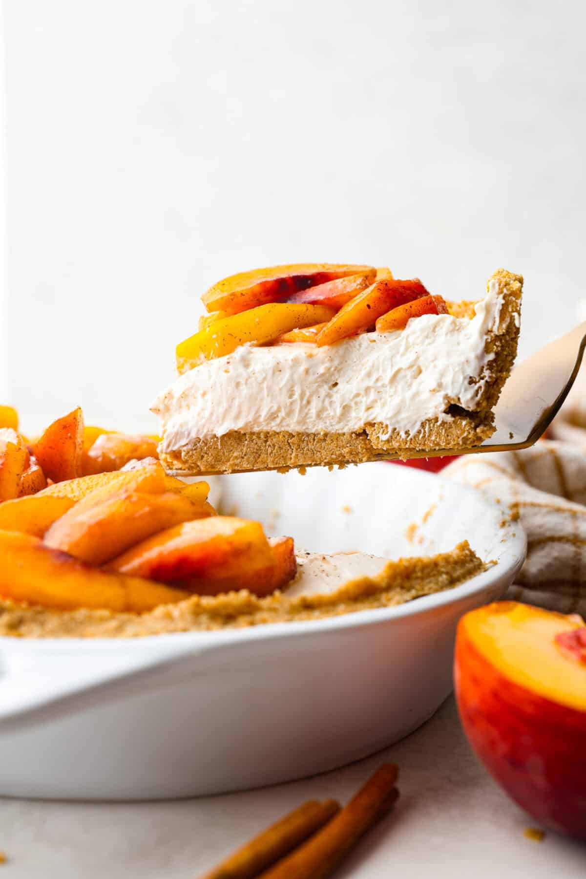 Side shot of a slice of fresh peach pie being lifted out of the pie pan. 