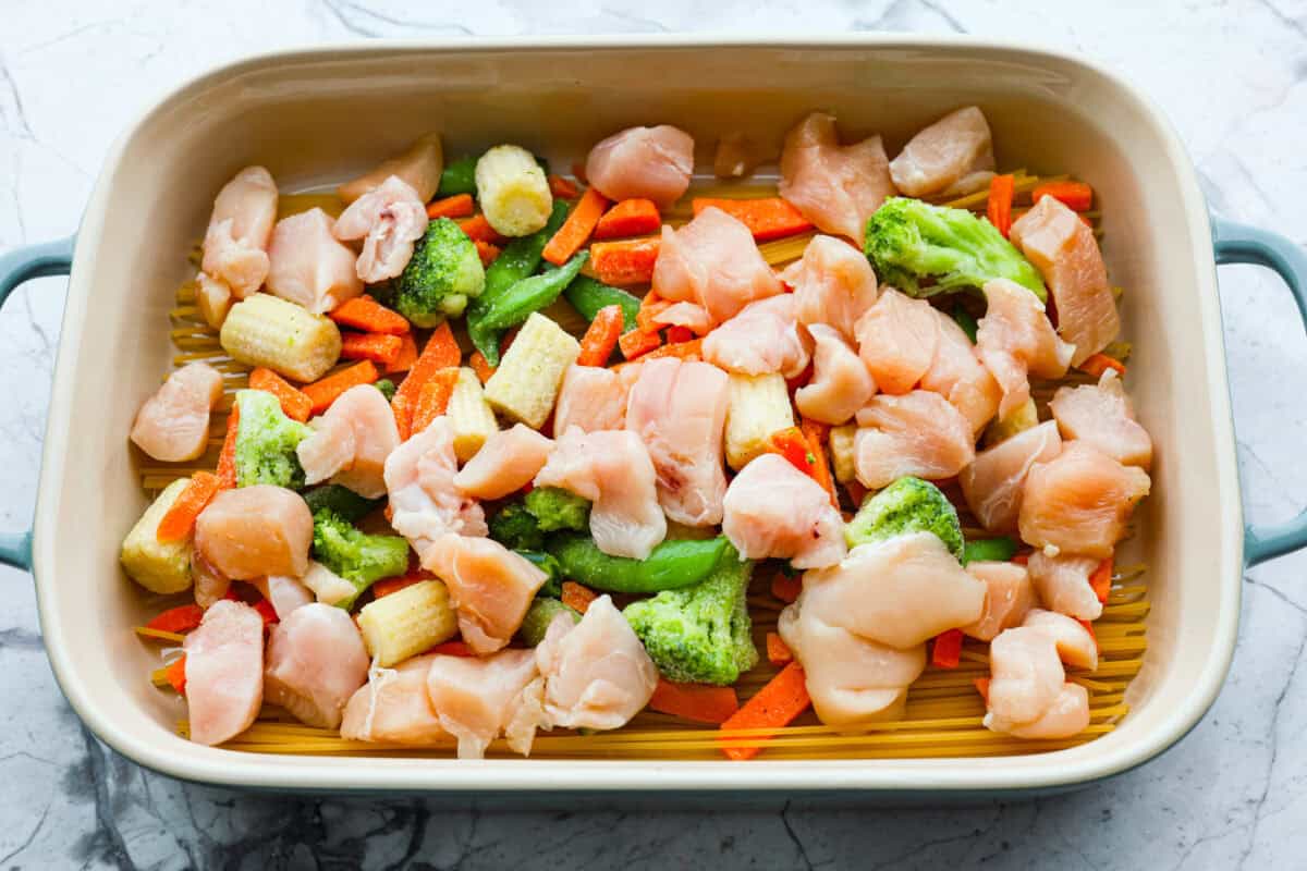 Overhead shot of chicken added to the veggies and noodles. 