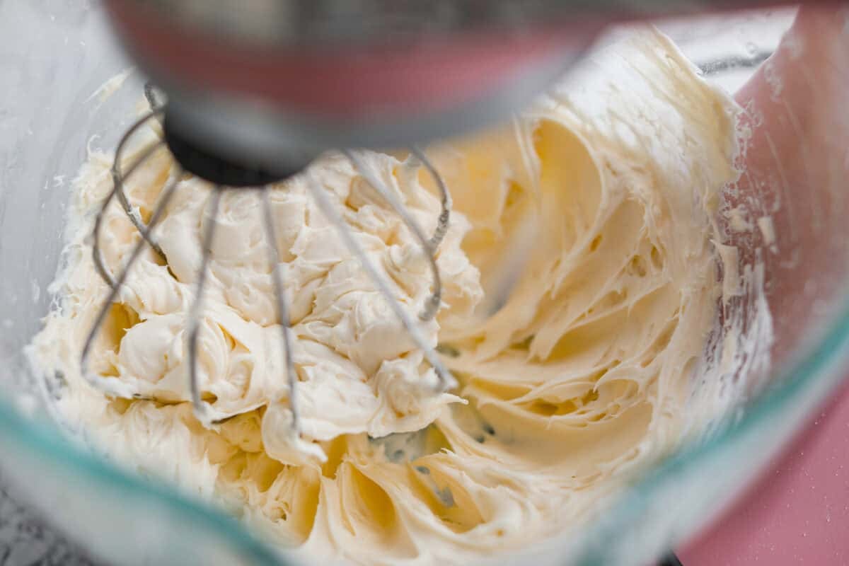 Cream cheese filling ingredients being mixed together in a stand mixer. 