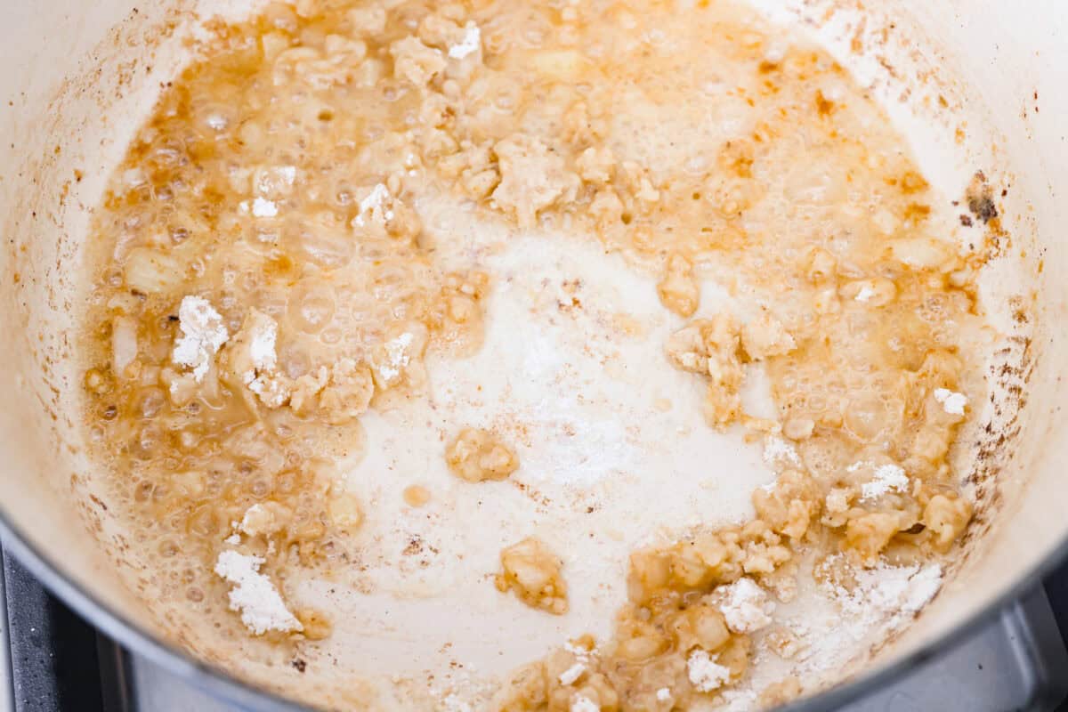 Overhead shot of onions cooking in a pot with butter, garlic, and flour. Creating a roux for the base of Swedish meatball soup. 