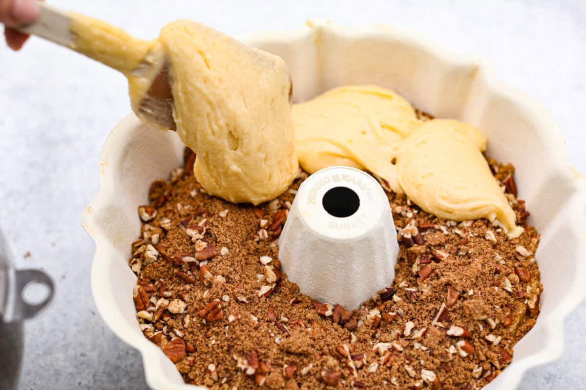 Overhead shot of someone scooping the rest of the cake batter over the filling in the bundt pan. 