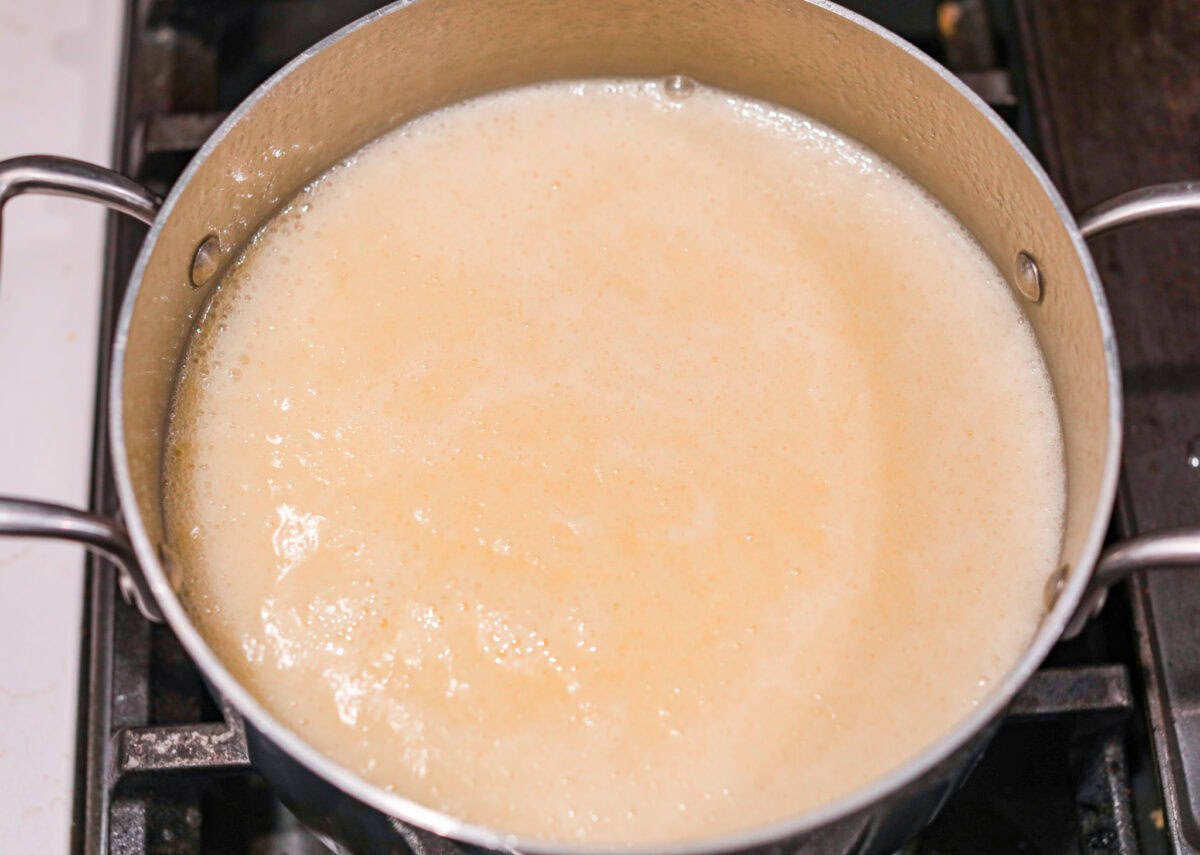 Overhead shot of the sugar, butter, salt, and evaporated milk being heated on the stove to a rolling boil. 