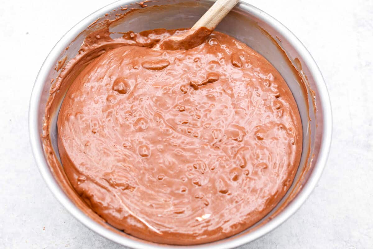 Overhead shot of someone stirring together the chocolate mixture with the warm milk mixture. 