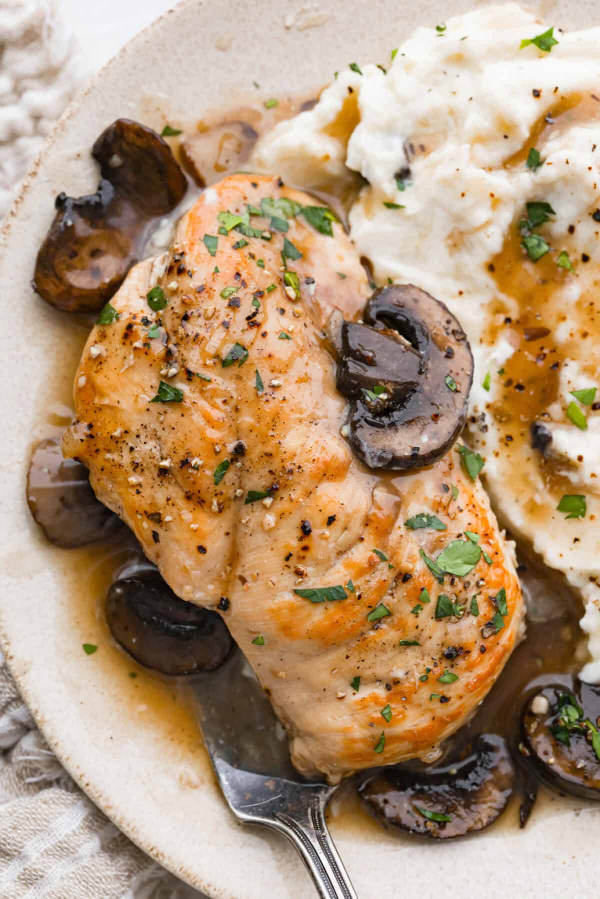 Plated crockpot chicken marsala next to mashed potatoes. 