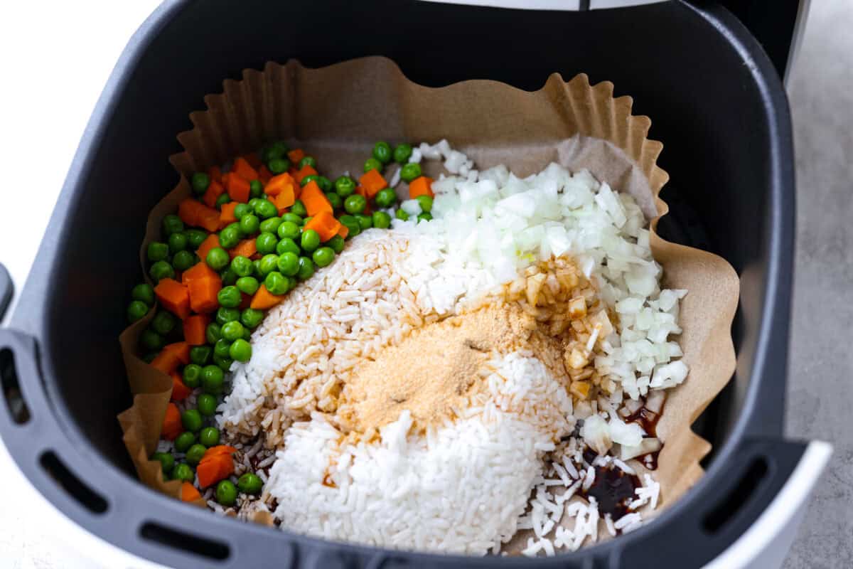 All of the ingredients for the rice, except the eggs, added to the liner in the air fryer basket. 