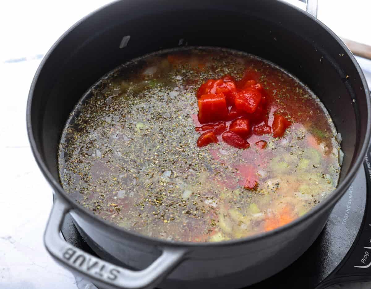 Vegetable broth, tomatoes, and seasonings added to the pot.