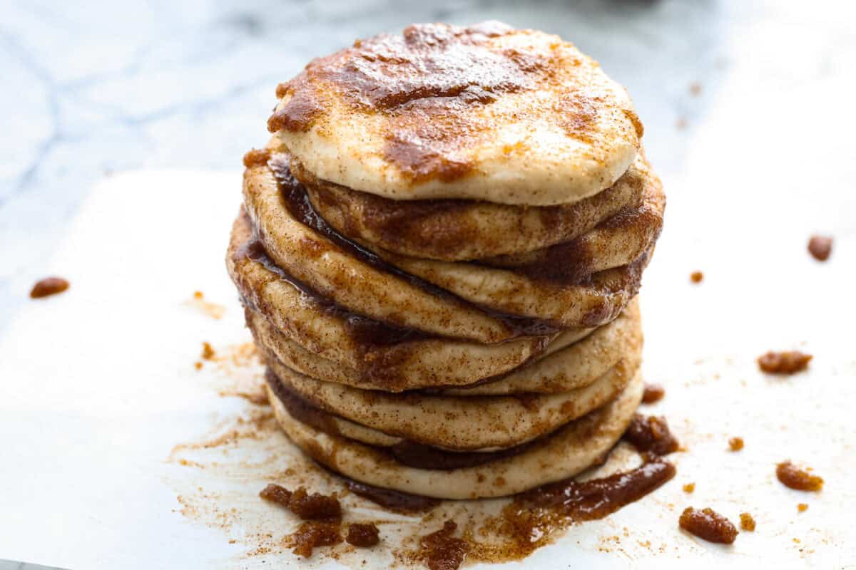 Angle shot of a stack of flattened dough balls that are drenched in butter, cinnamon and sugar. 