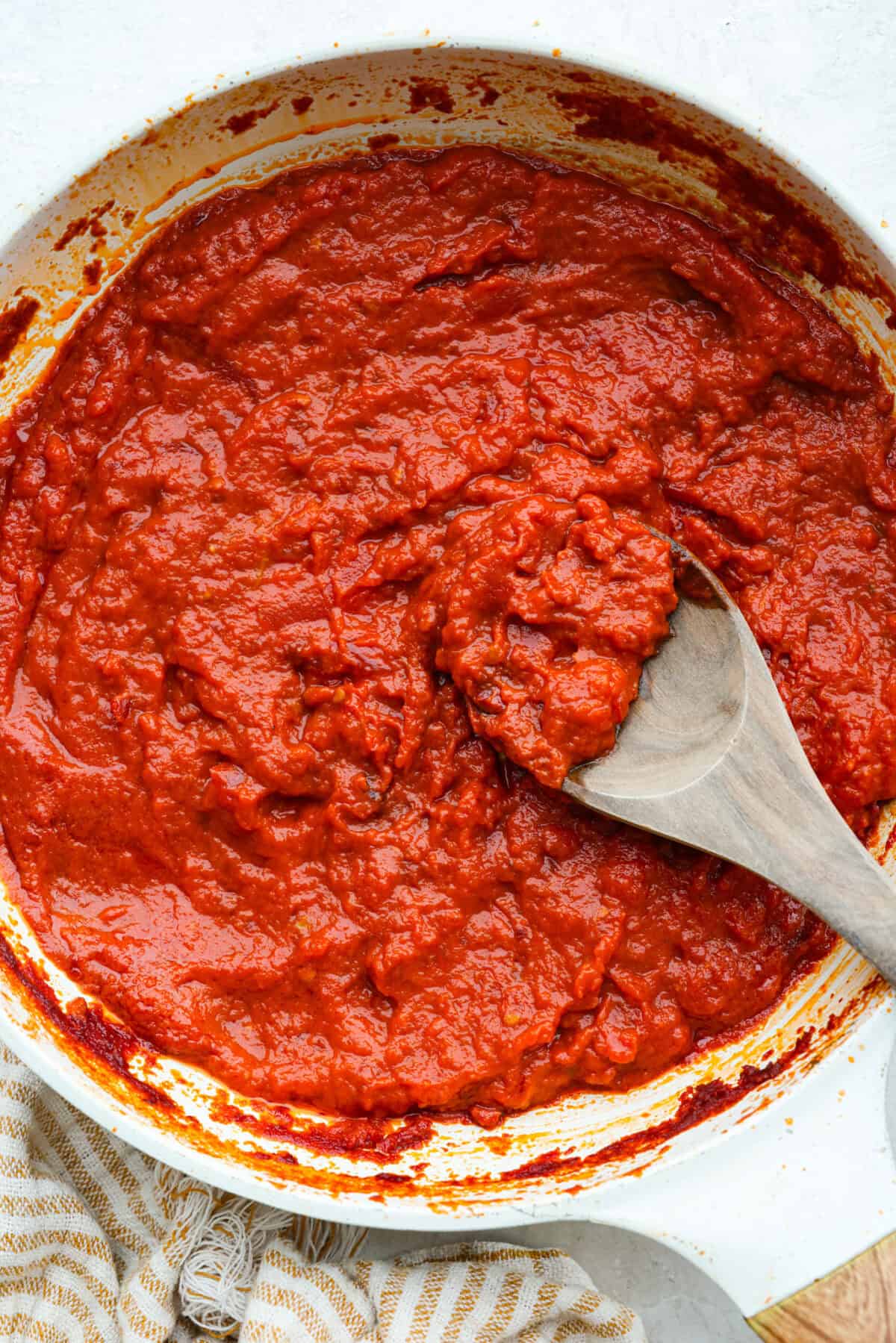 Marcella Hazan's tomato sauce with a wooden spoon in a sauce pan. 
