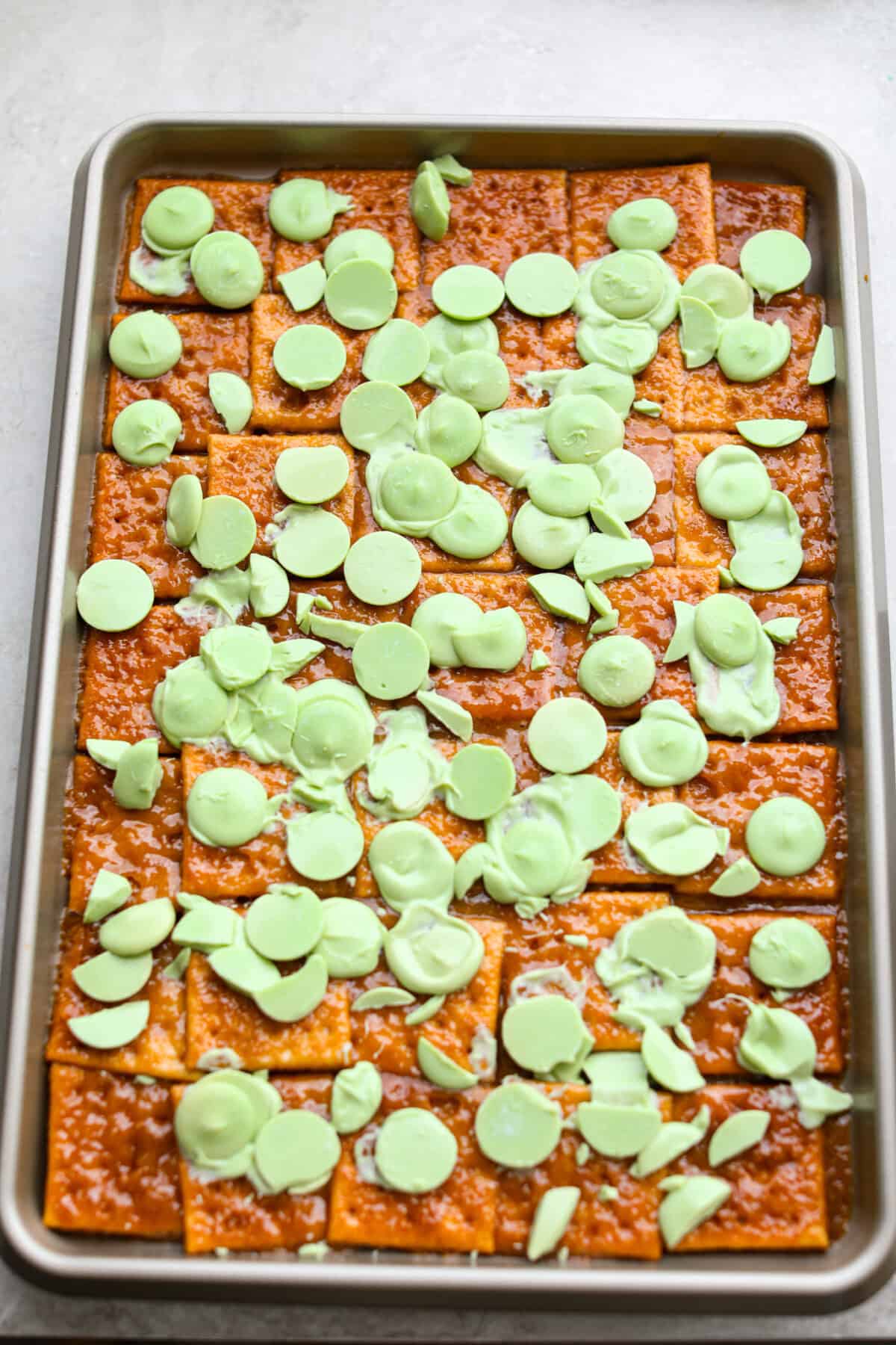 Light green candy melts spread over the hot toffee on the crackers.