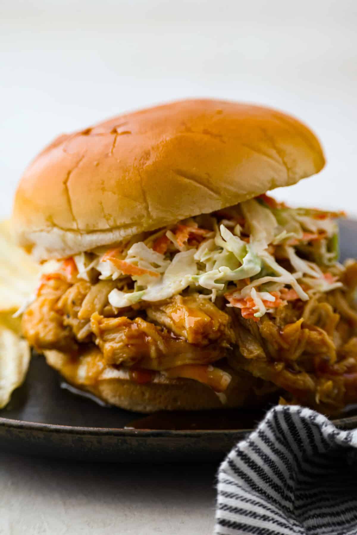 Side shot of sandwich with slow cooker shredded bbq chicken and coleslaw. 