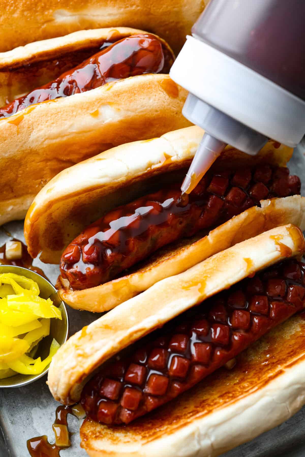 Someone squeezing J Dawgs sauce on a hot dog.