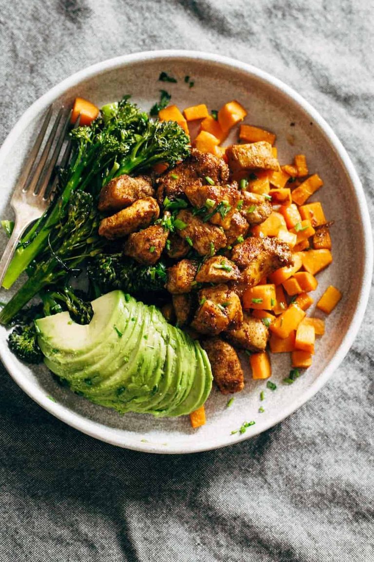 Sheet pan chicken, sweet potato, broccoli, and avocado on a plate.