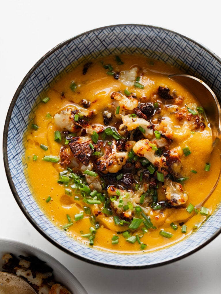 Sweet potato soup in a bowl with roasted cauliflower on top.