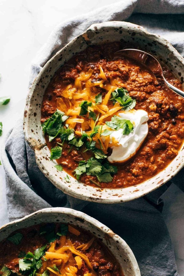 Vegetarian chili in a bowl with sour cream, cheese, and cilantro on top.