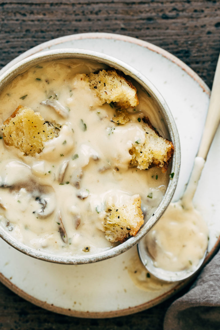 Creamy mushroom soup in a bowl with croutons on top.