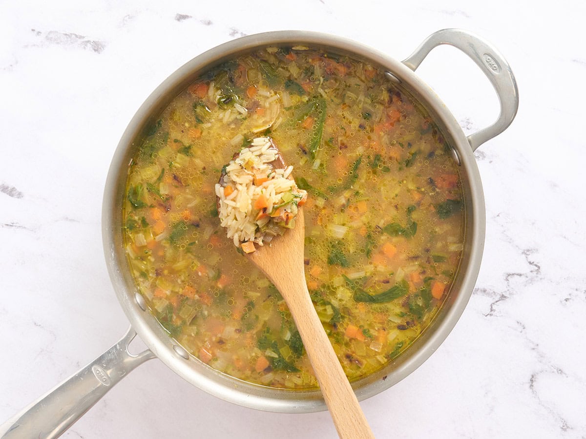 Some brothy rice on a wooden spoon.