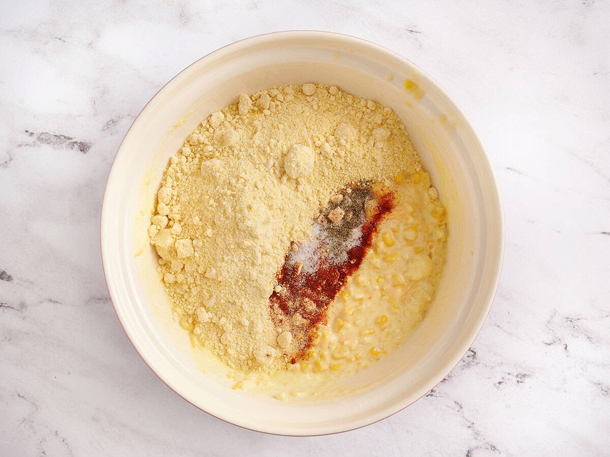 Adding the cornbread mix and seasonings to the bowl.