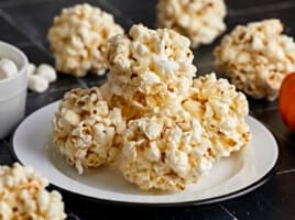 Close up side view of popcorn balls stacked on top of a plate.