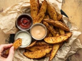 A hand dipping one oven baked steak fry into ranch dressing