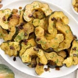 Roasted acorn squash with raisins and fresh parsley on a white serving platter.