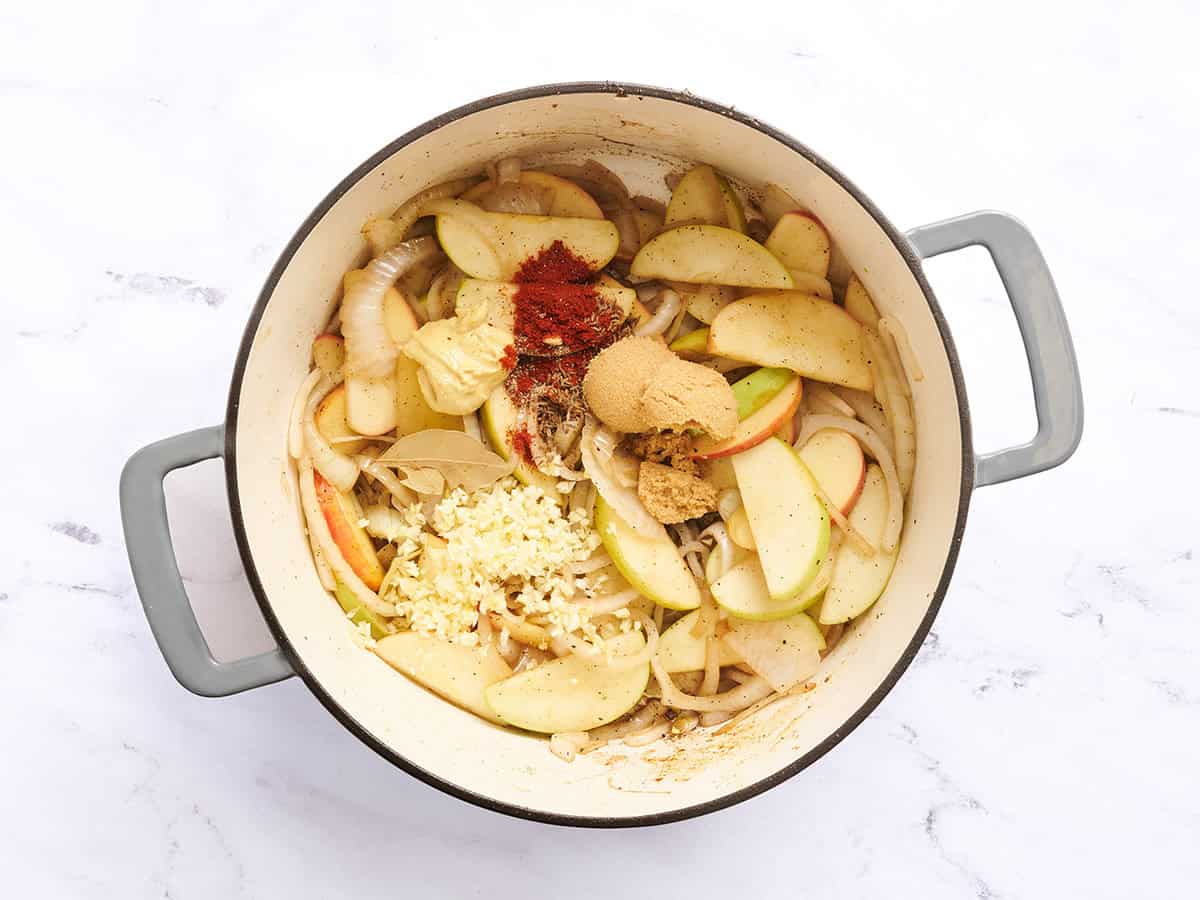 Spices added to a dutch oven of onions and apples.