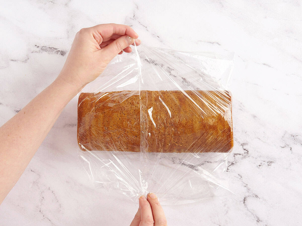 hands putting plastic wrap on pumpkin roll to help it keep its shape
