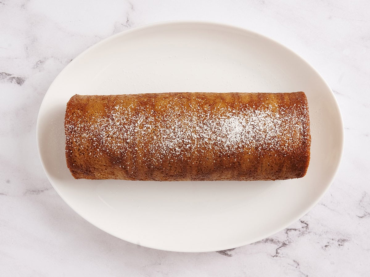 pumpkin roll dusted with powdered sugar and ready to be sliced