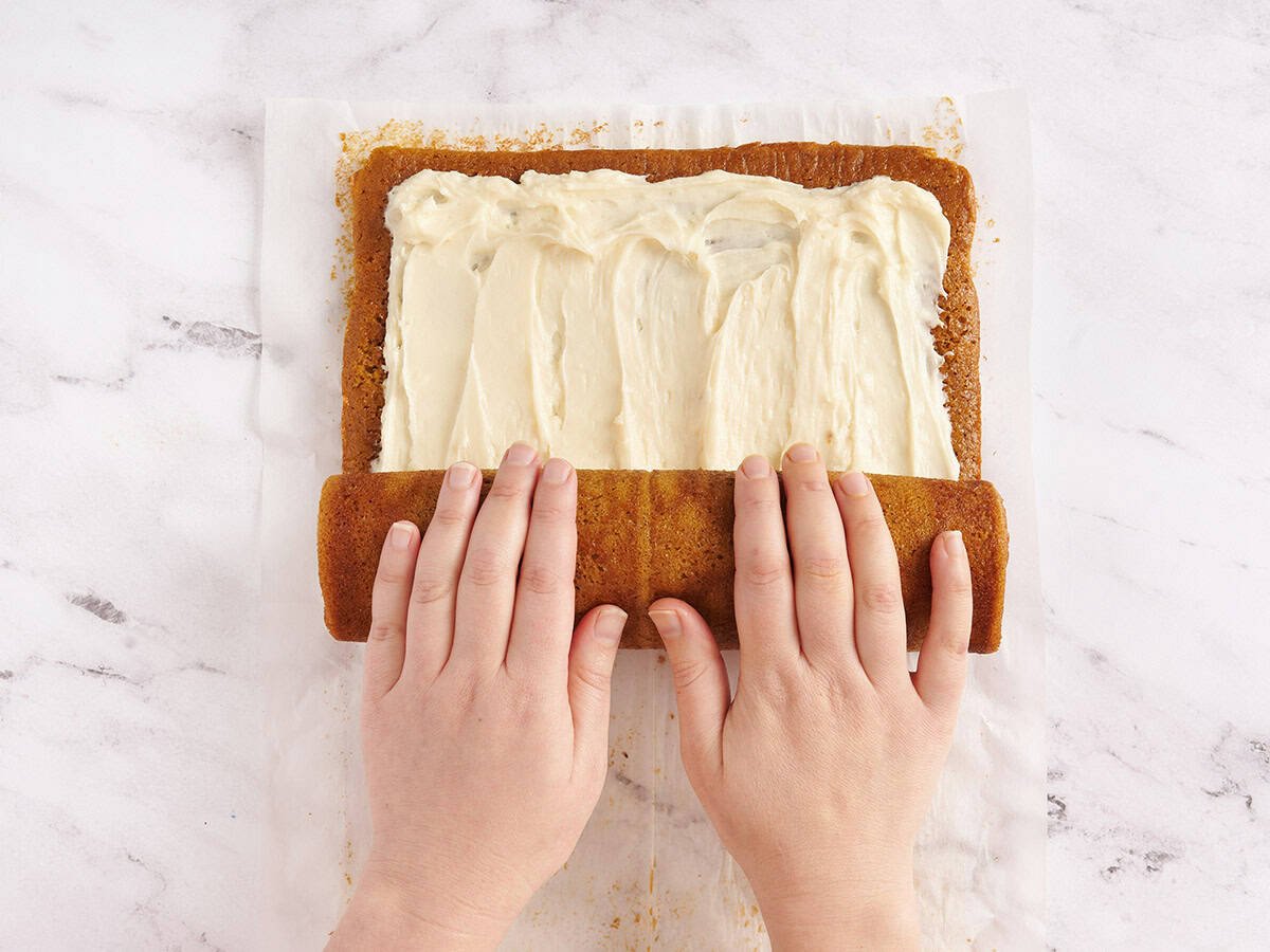 hands starting to roll up pumpkin roll