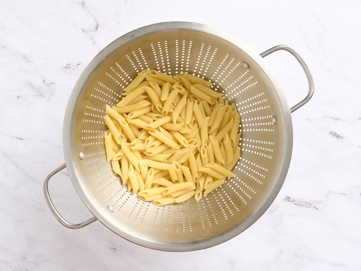 Cooked penne pasta in a colander.