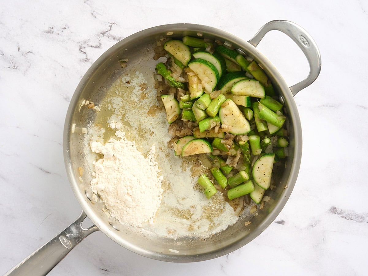Melted butter and flour added to a skillet of sauteed veggies.
