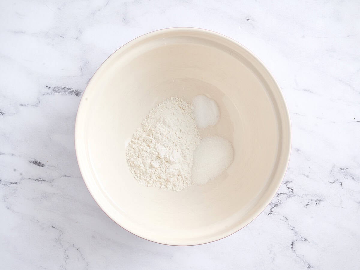Flour, salt, and sugar in a white bowl.