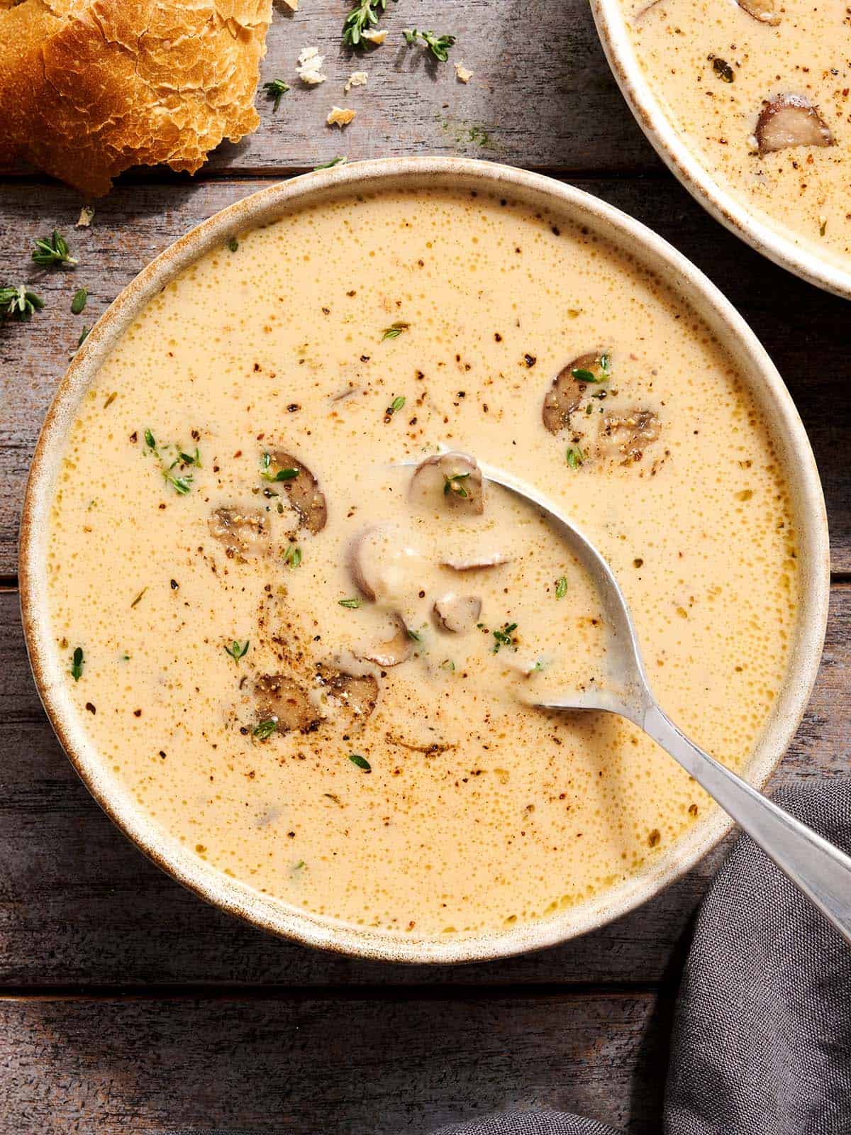 Overhead view of creamy mushroom soup in a bowl with a spoon.