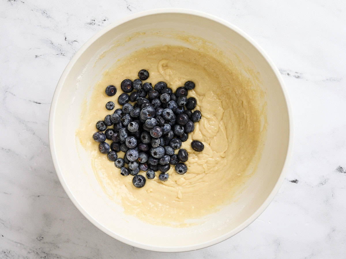 Blueberries added to the batter for lemon blueberry muffins in a mixing bowl.