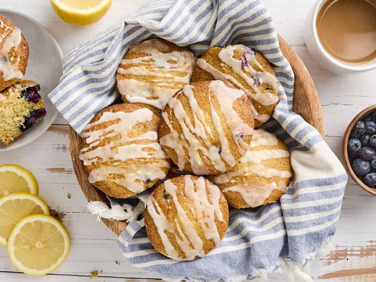 Overhead view of lemon blueberry muffins in a kitchen towel-lined basket.