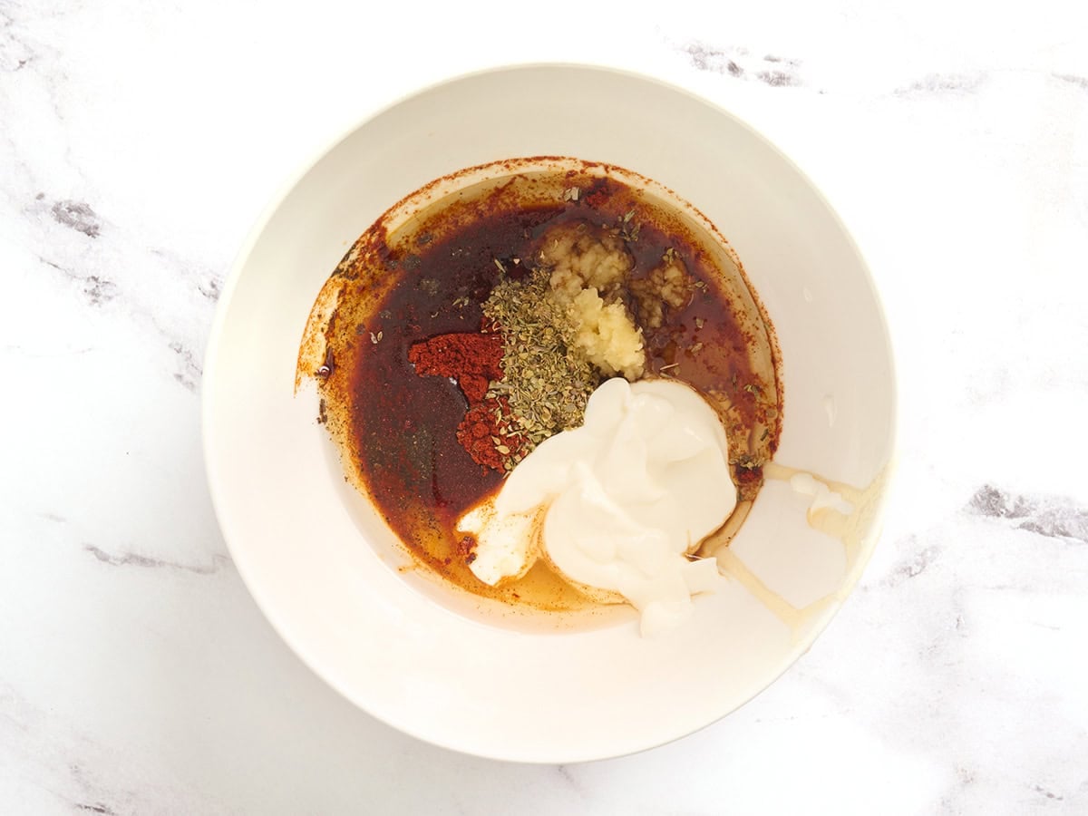 Oil, yogurt, garlic and seasonings in a bowl.